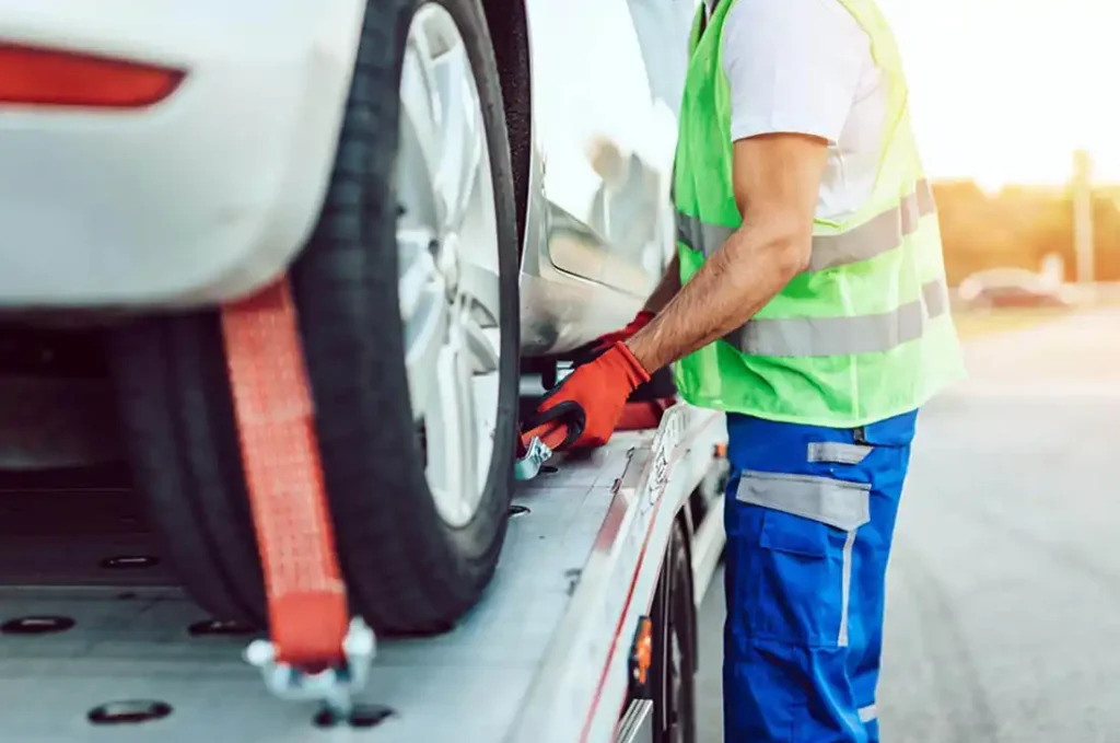 close-up of tow truck driving securing a car on a flatbed