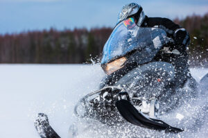 person riding a snowmobile and throwing off a cloud of snow