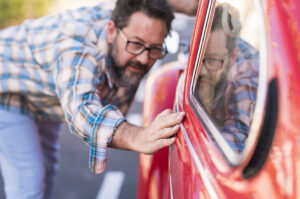 man leaning over and stroking the side of his car