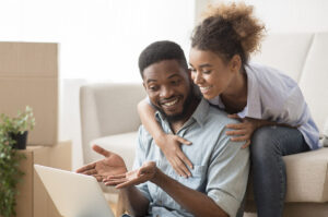 Young couple looking at a laptop sitting beside packing boxes