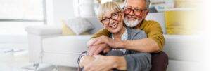 older couple sitting on the floor in front of the couch hugging and smiling