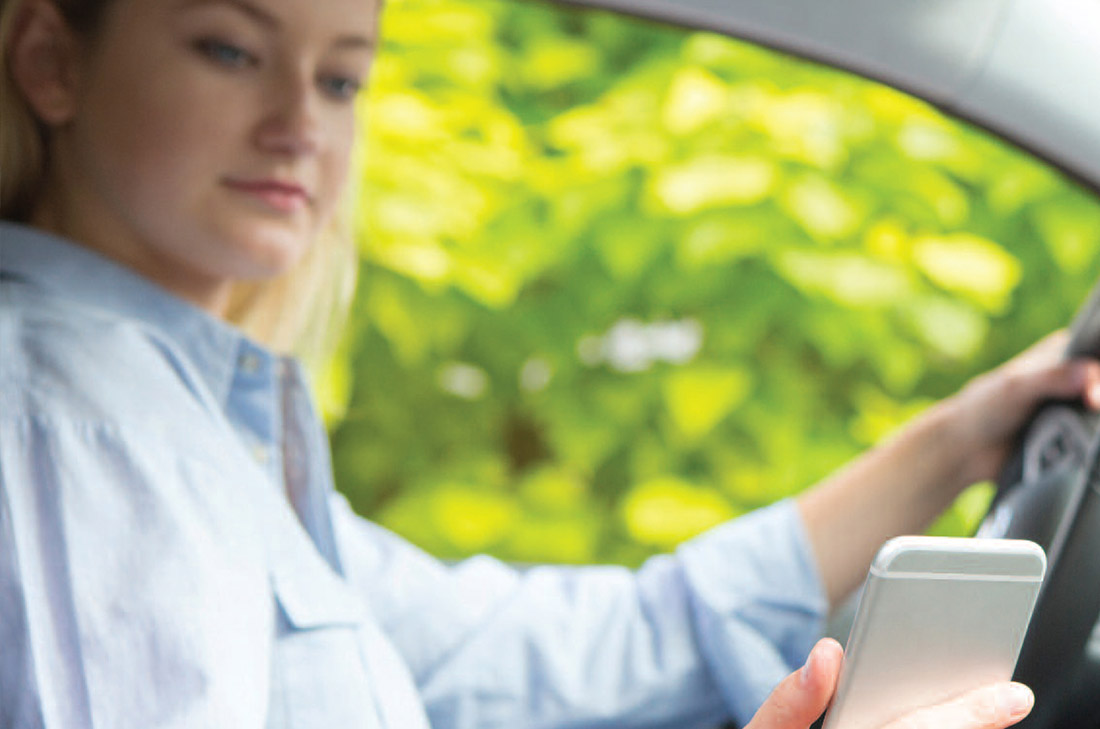 Young woman looking at her phone while driving