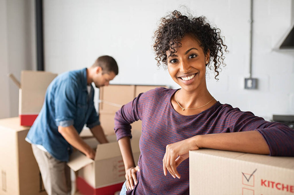 Woman leaning on cardboard box while moving house