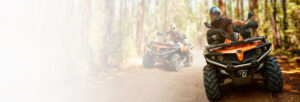 two guys riding their atvs through the woods