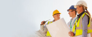 Group of three people in hard hats and safety vest on a construction site