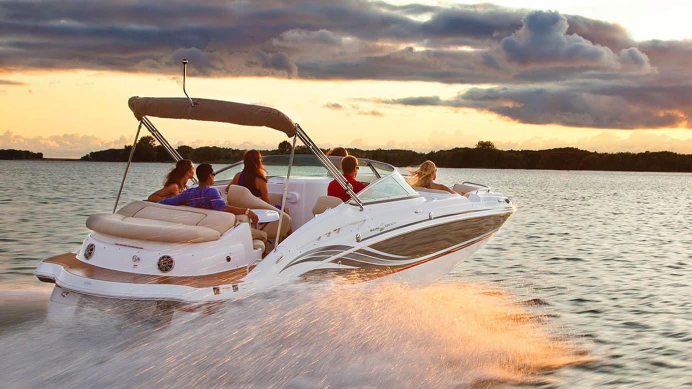 image of family on large motorboat speeding across a lake towards setting sun with dramatic clouds in the sky