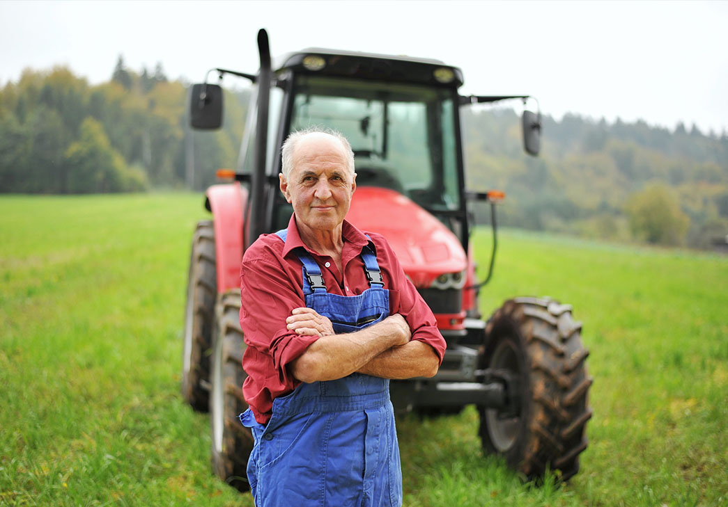 Proud farmer standing in front of his red tractor