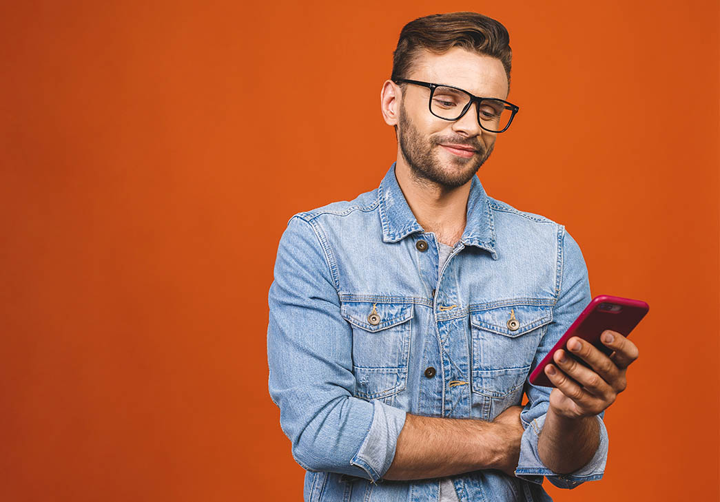 man looking at his smartphone against an orange background