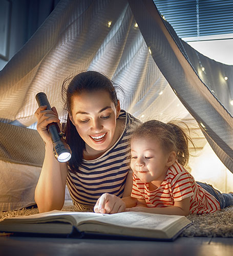 mother and daughter in tent-fort reading a book