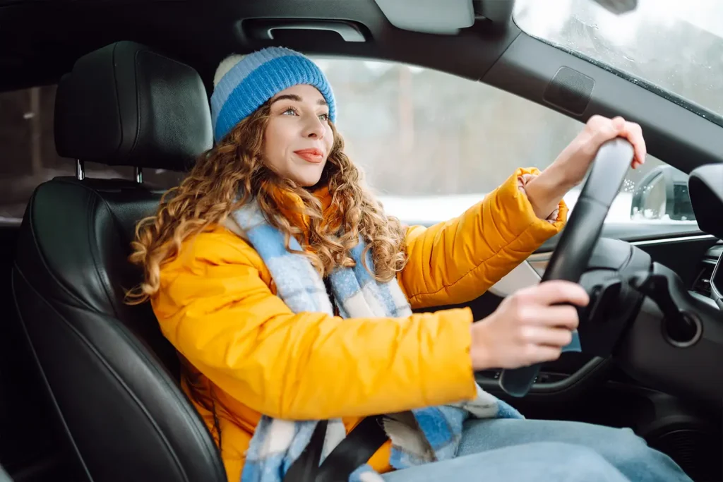 female driving dressed in winter gear in a car