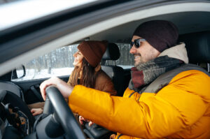 Couple driving in winter wearing warm clothing