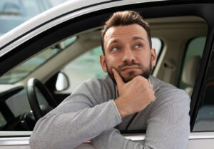 man sitting in his car looking thoughtfully out of side window