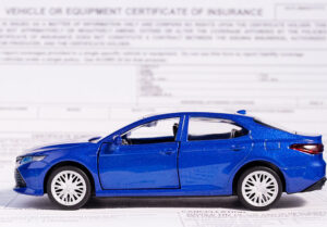 Blue car sitting on an insurance policy document page