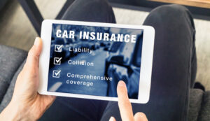 Closeup of a person holding a tablet with car insurance information displayed on it.