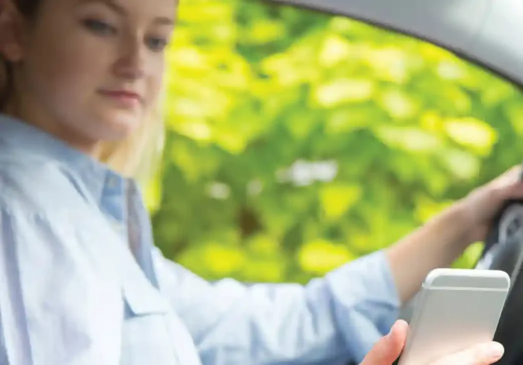 Young woman looking at her phone while driving