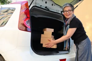 Happy woman loading boxes into SUV trunk